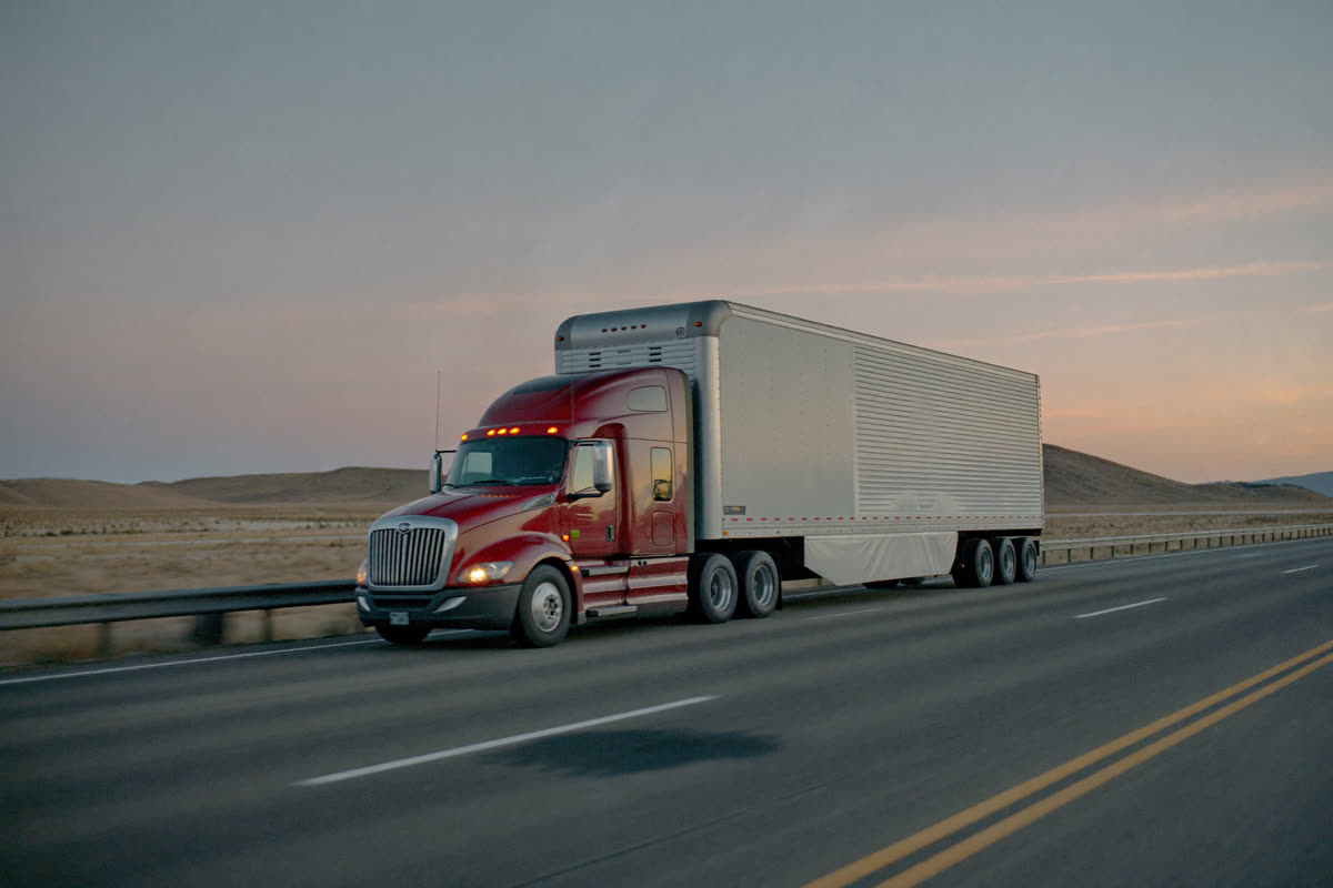 AI-generated photo: a red semi truck on an empty interstate at sunset