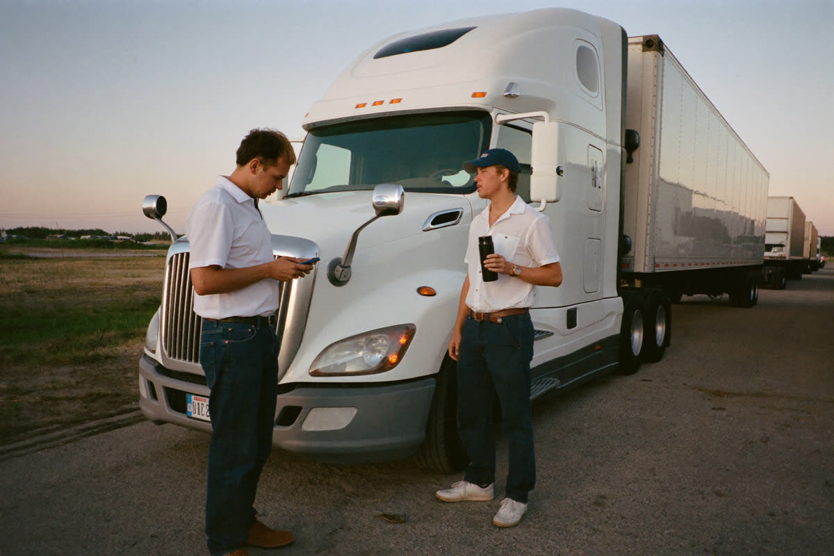 AI-generated photo: two team drivers talking next to their semi truck at sunrise